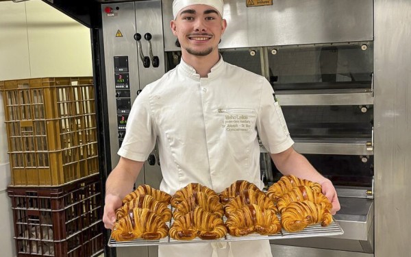 Croissant 3 bakker  haalt verse croissants uit de oven van een boulangerie.jpg
